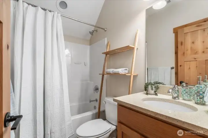 View of upper level full bathroom with quartz countertops.