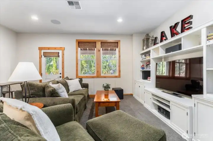 View 1 of lower level bonus/media room with doors opening to the lower level outdoor living area.