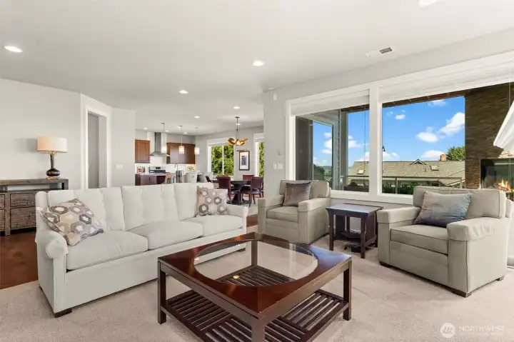 Open living room features expansive windows, comfortable gathering space, and a seamless connection to the kitchen, dining area, and covered outdoor living space. Open living room features expansive windows, comfortable gathering space, and a seamless connection to the kitchen, dining area, and covered outdoor living space.