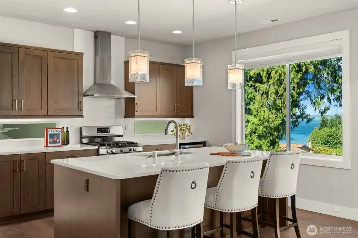 Well-appointed kitchen features a spacious island with seating, gas range, and views through large windows. Well-appointed kitchen features a spacious island with seating, gas range, and views through large windows.
