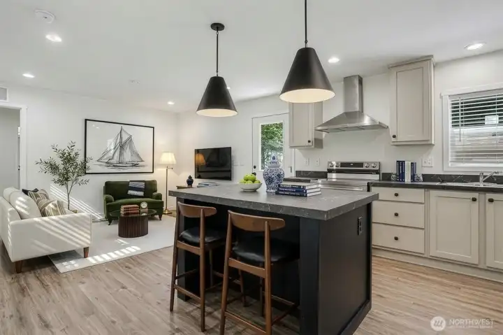 Virtually staged view of the kitchen with island and living space in the background Virtually staged view of the kitchen with island and living space in the background
