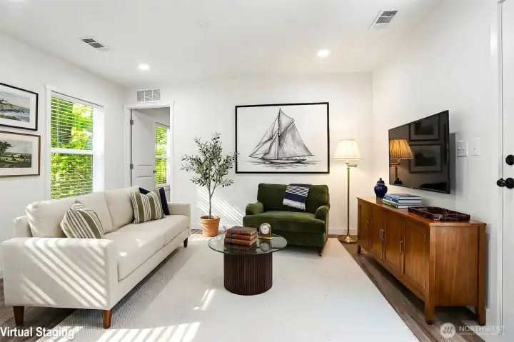 Virtually staged living area adjacent to the kitchen with primary bedroom opening beyond Virtually staged living area adjacent to the kitchen with primary bedroom opening beyond