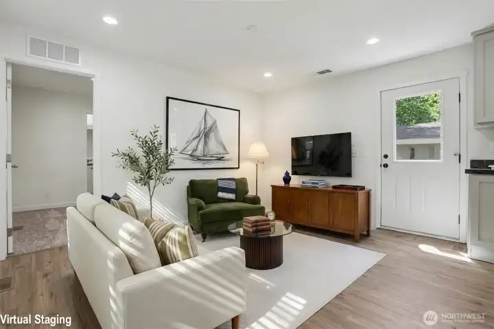 Virtually staged view of living space with back door on the right and primary bedroom door on the left of photo Virtually staged view of living space with back door on the right and primary bedroom door on the left of photo