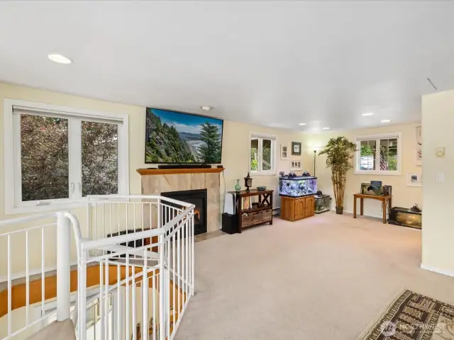 Large open Living Room with sweeping views of the lake, fireplace and Door out to Deck #1 for enjoying the outdoors 12 months a year - with spiral staircase to the lower levels.