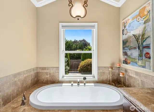 Primary ensuite soaking tub with picture window to gardens