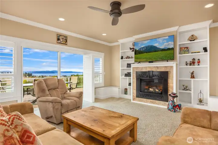 Custom built-ins frame the fireplace, with window seats on either side offering hidden storage and a cozy spot to relax while enjoying the Hood Canal view.