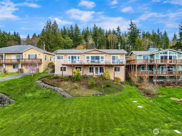 Rear exterior featuring a large view deck above and covered patio below, overlooking the terraced backyard.
