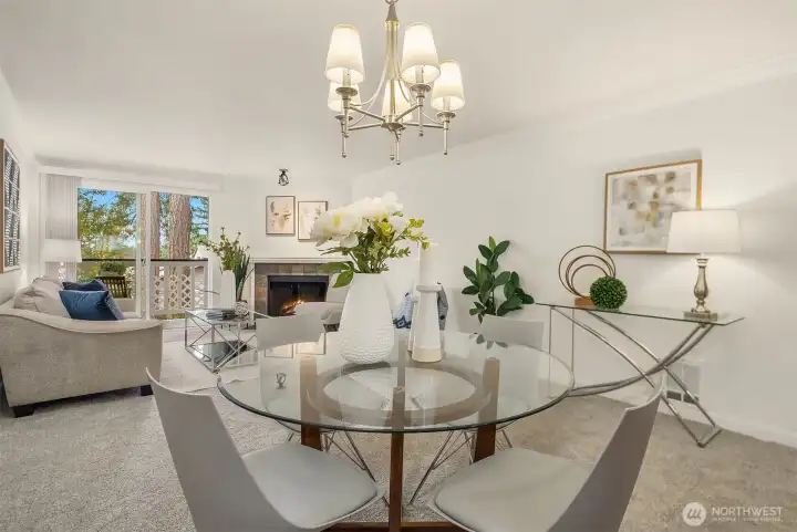 From the dining area, a view into the living room featuring a wood-burning fireplace and access to the deck beyond