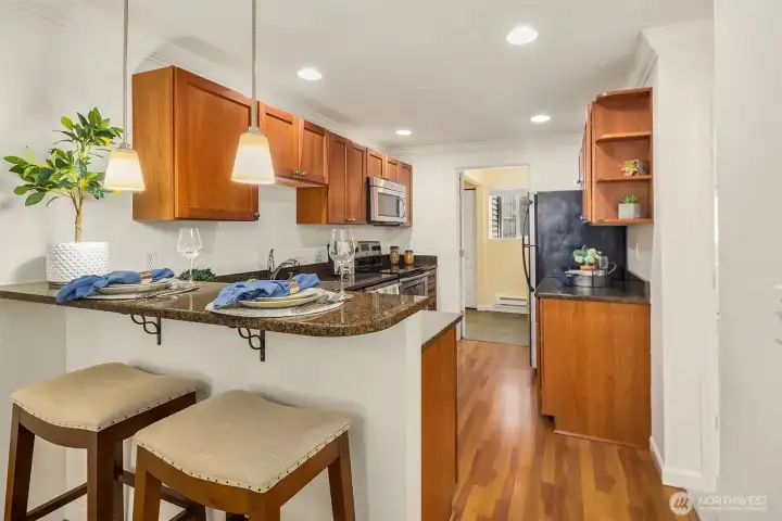 From the dining area, a welcoming view into the kitchen, featuring an eating peninsula and warm pendant lighting