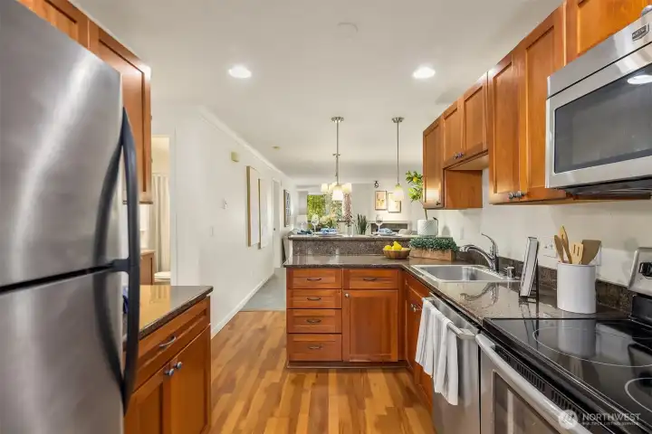 Kitchen featuring cherry cabinetry, granite countertops, stainless steel appliances, and durable laminate flooring