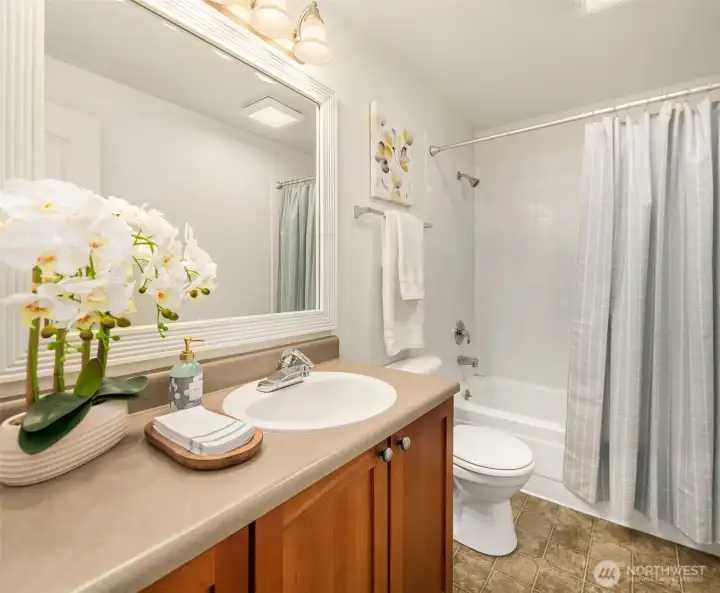 The secondary bathroom offers a tub/shower combo and a spacious cherry-cabinet vanity