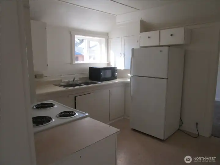 Step-saver kitchen has range/oven, refrigerator, and microwave.