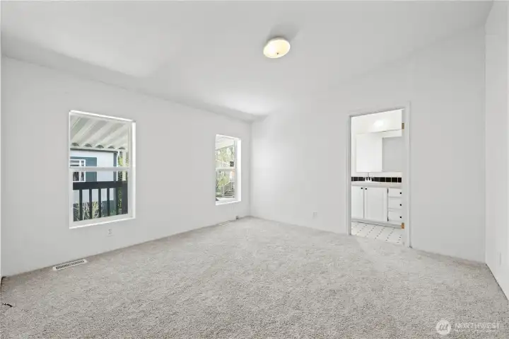 Primary bedroom has big windows and tall ceilings too.