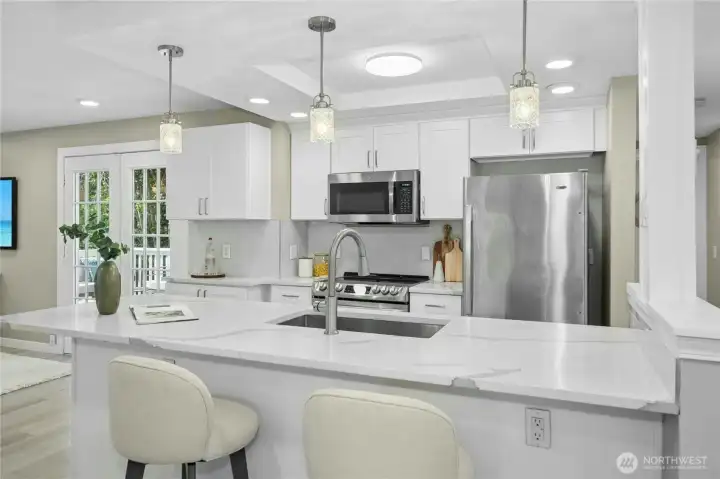 Beautifully updated contemporary kitchen with quartz countertops, stainless appliances, a large prep island and task lighting.