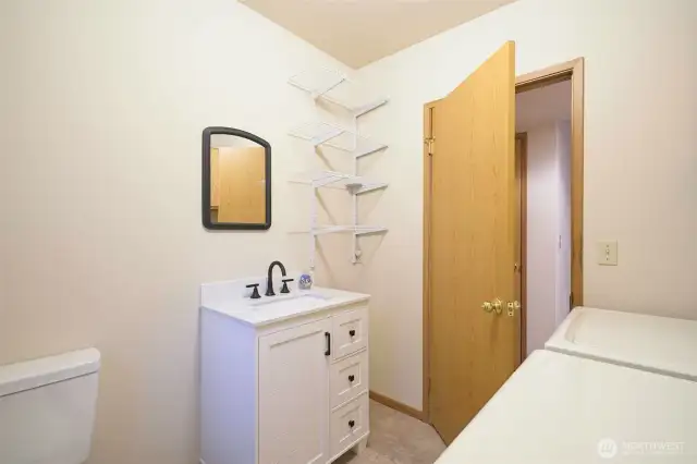 Half bath and laundry room on the lower level with a new vanity and a toilet.