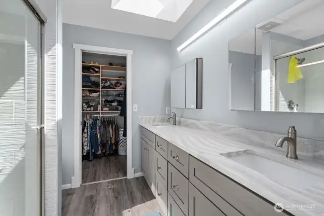 Spacious quartz bathroom countertop with new double sink vanity, LVP floors and skylight for perfect lighting
