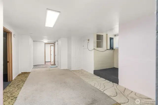 Mechanical room door on left. Additional staircase with blue carpet to kitchen on right.