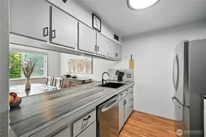Kitchen features updated counters and new appliances.  With eating bar open to dining space.