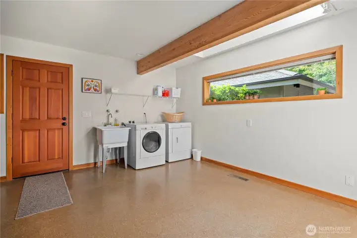 Large laundry and mud room with a solid wood door leading out to the garden patio. Notice the exposed beam, the skylight and all the solid wood accents! The updated heatpump furnace & A/C and the updated water heater are in this room as well around the corner.