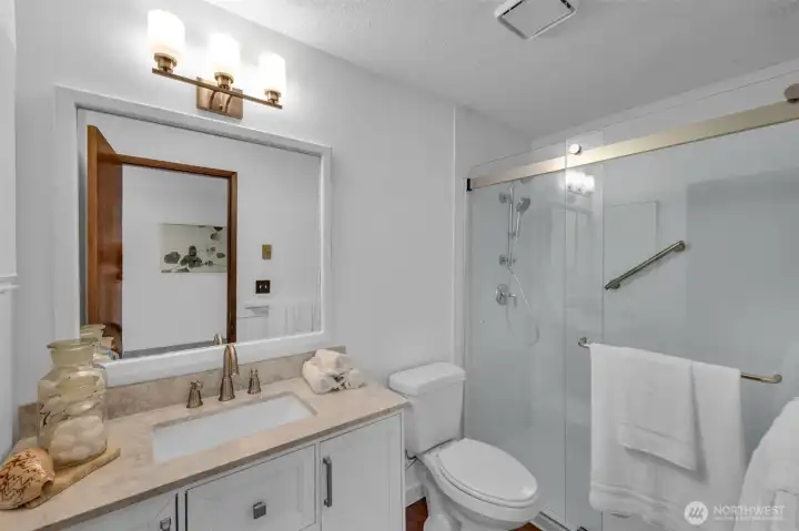 The attached primary bathroom with new lighting, new vanity and luxury step in shower.