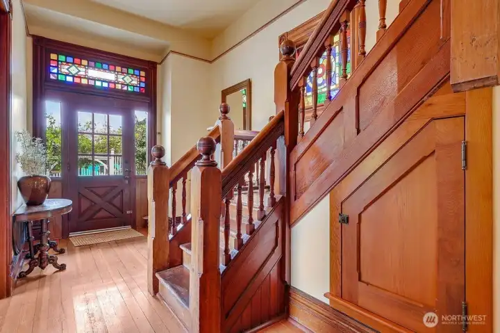 Stairwell showing the front door entry with the front door stained glass adding to the eloquence of home.