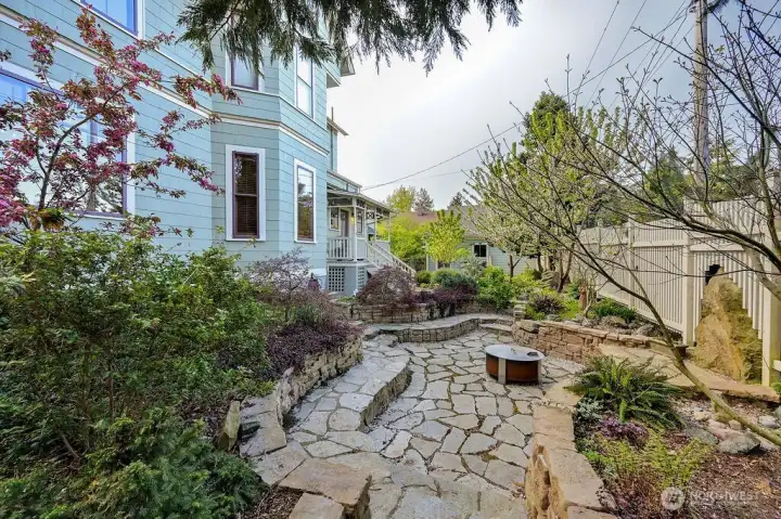 Stone seating area and fire pit, a path leads to the mudroom entry of the kitchen.