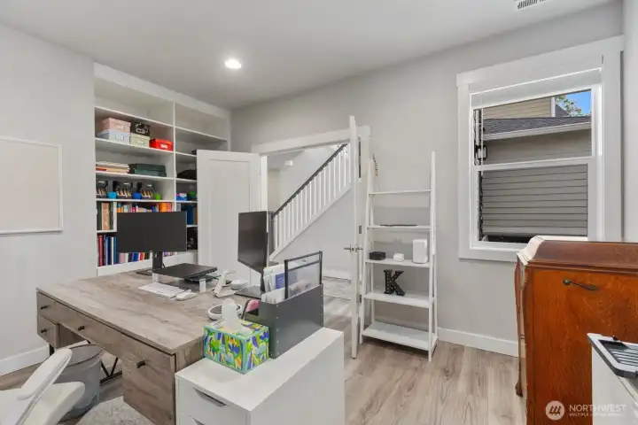 Office off the entryway with built in shelving and windows for lots of natural light
