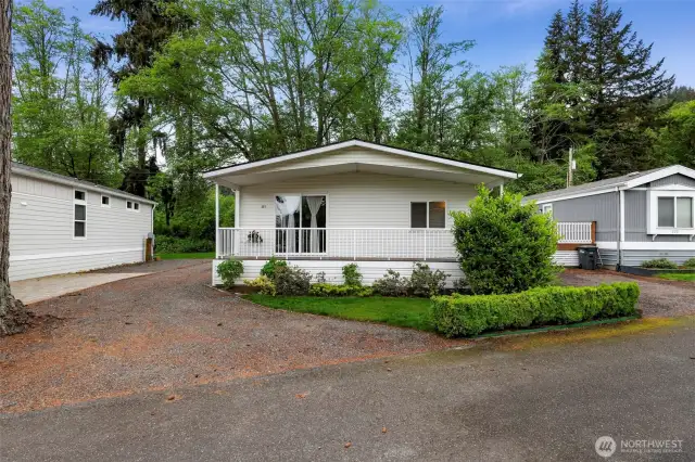 The welcoming front exterior of this manufactured home in Bellingham’s Lake Samish Terrace 55+ community is framed by tidy landscaping, a wide driveway, and a covered front porch. Crisp white vinyl siding and natural surroundings blend modern convenience with Pacific Northwest charm.