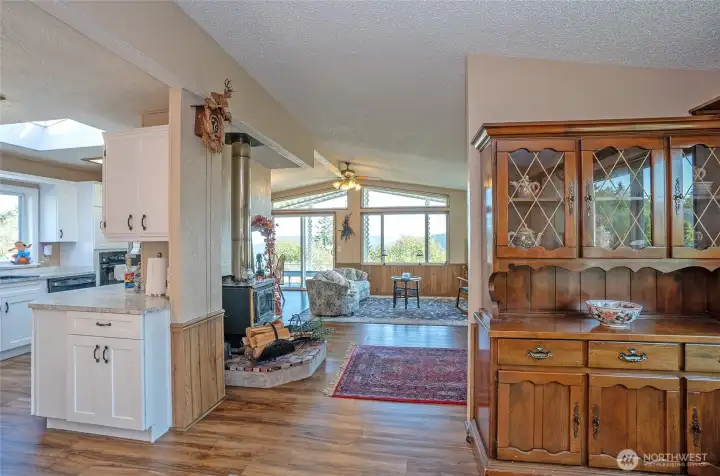 Open sightlines from the dining area to the living and kitchen, featuring vaulted ceilings and a bright, airy feel.