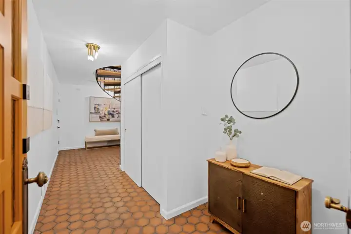 A welcoming covered porch shelters the entrance from the rain with just a single step leading into the home. Beautiful wooden French doors create an inviting first impression and fill the entry with warmth. Inside, a level and wide hallway provides an easy transition to both the staircase and the elevator, offering comfortable access for everyday living.