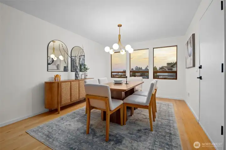 The formal dining room is an inviting place to gather for dinners with loved ones or to host guests with elegance. A wall of beautifully placed windows bathes the room in natural light, creating an uplifting setting for everyday meals and special occasions. A sophisticatedly modern chandelier adds a graceful focal point and elevates the room with a touch of understated luxury. A door leads directly to the view deck, making it easy to extend your meals and conversations outdoors.