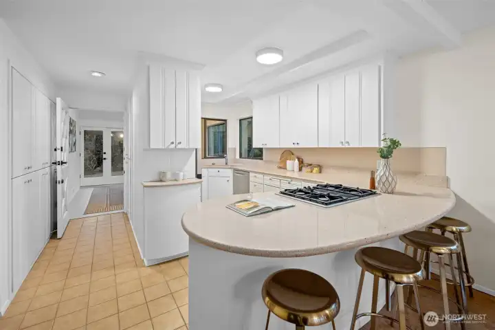 This bright, welcoming kitchen features new lighting and light airy colors that make the space feel open and uplifting. A gas cooktop with a hidden vent keeps the lines clean, while the wrap around layout offers an efficient and thoughtfully designed use of space with an abundance of cupboards for effortless storage. A charming Dutch door opens to the sun room and back yard, bringing in fresh air and an easy indoor outdoor connection. The curved peninsula offers comfortable seating for relaxed weekend breakfasts or casual gatherings with friends.