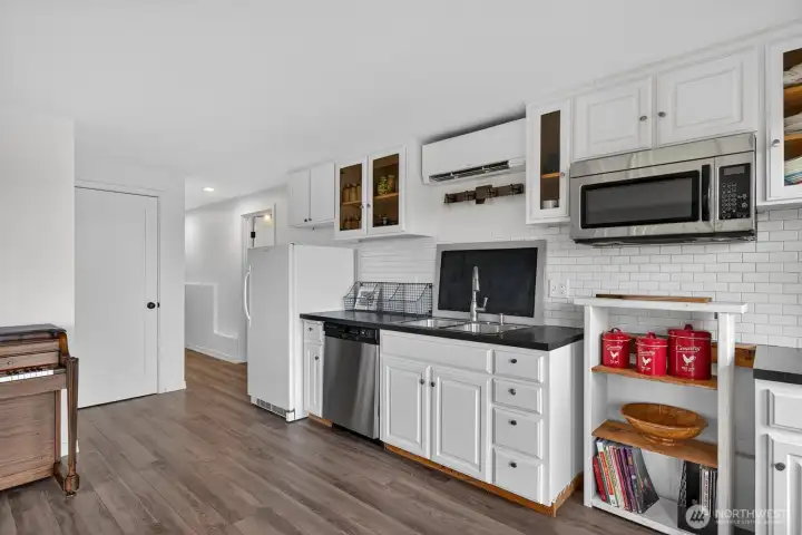 Lower level. Bedroom 2 is behind the piano and the open door beyond the refrigerator is the bath and laundry...