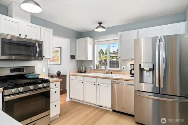 Stainless steel appliances with gas stove top, microwave, dishwasher, large fridge and pantry area.