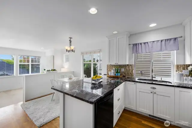 Charming kitchen with granite counters, white cabinetry, and dining nook.