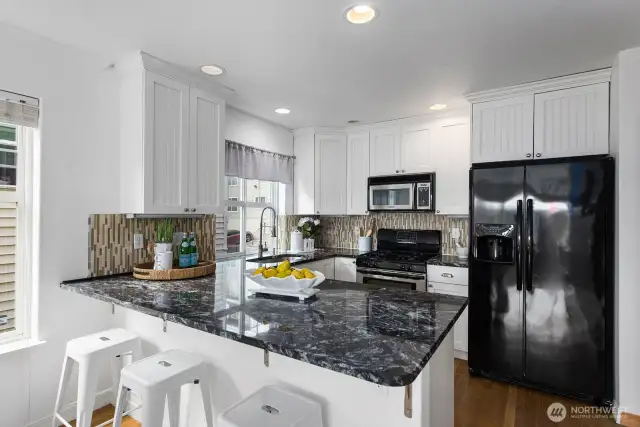 Beautifully designed kitchen with granite countertops, to ceiling cabinets, full-height backsplash, gas stove, and center island.