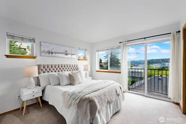 Luxe primary suite with Juliette balcony, sliding glass doors, and city scape views.