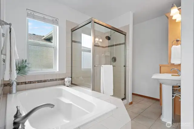 Your primary ensuite, with soaking tub, glass surround shower, and built-in cabinetry.