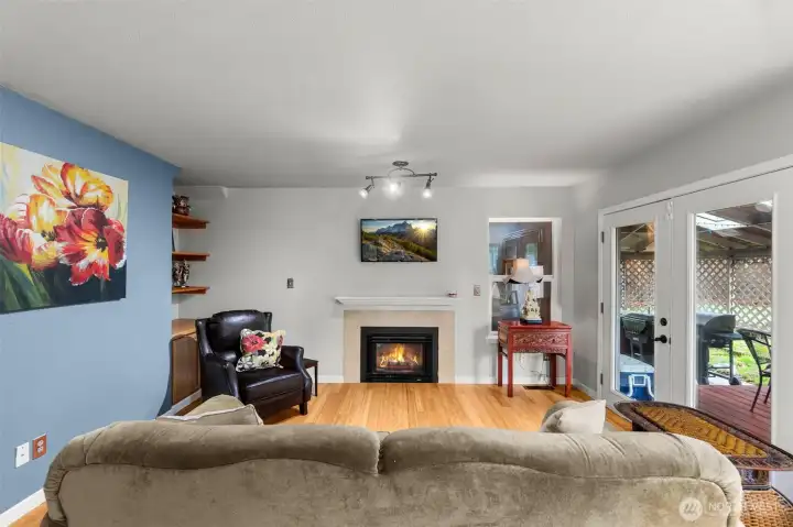 Looking into the formal living area with gas fireplace, built in book cases, French doors exiting out to covered patio