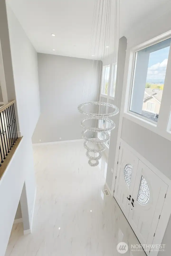 View from the loft area to the main floor, showcasing high ceiling entrance and the living room