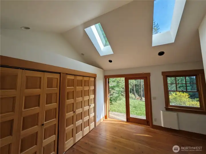 The primary bedroom with wall of closets, skylights, and french doors to a private deck. Perfect for stargazing.