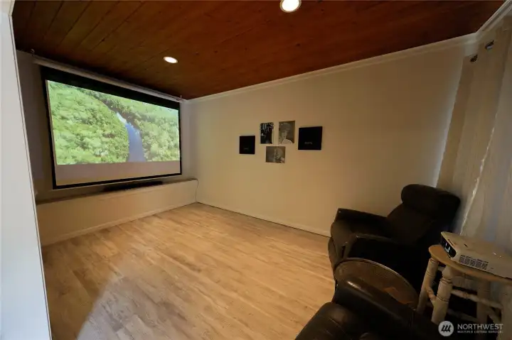 A dedicated theatre room on the main level offers the perfect setup for movie nights, complete with a large projector screen and a warm wood ceiling. A dedicated theatre room on the main level offers the perfect setup for movie nights, complete with a large projector screen and a warm wood ceiling.