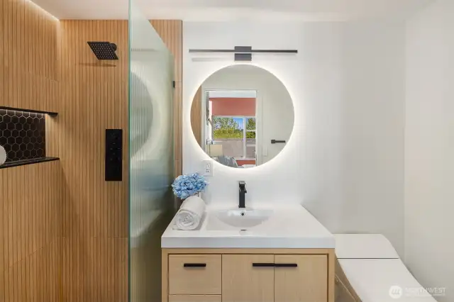 The primary bath was a $35K remodel. Plumbing and fixture layout was totally reconfigured and reimagined to make sense. The bathroom floor is Euro style with waterproofing and a slope towards the shower drain for easy cleaning. High end tile on floor and curbless shower. Kohler smart toilet. Backlit mirror, new vanity. Zoom in on that shower. There is a ceiling waterfall fixture and controls on the wall.
