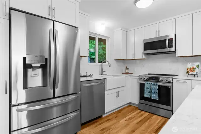 Completely remodeled kitchen with farmhouse trough sink, quartz countertops and stainless steel appliances feels crisp