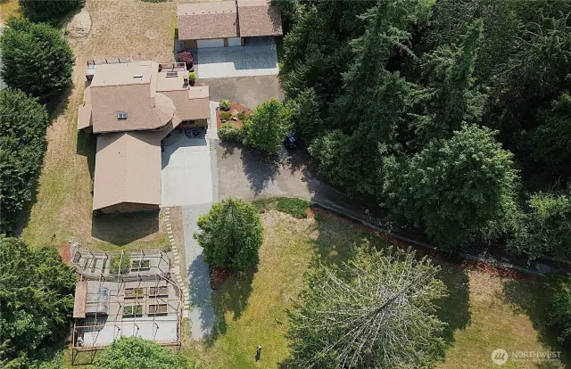 View of your raised garden, home with 3-car attached garage and detached 3-car garage with RV cover.