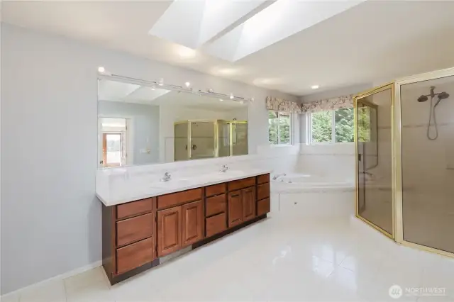 This five-piece primary bath blends luxury and tranquility, filled with natural light. Large windows and skylights invite the outdoors in, creating an oasis of calm.