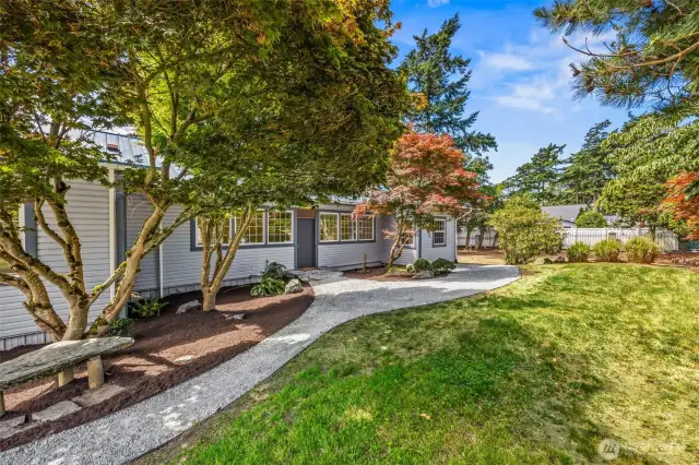 A peaceful pathway meanders through mature landscaping, guiding you to the welcoming front entrance of the home—offering charm, privacy, and a sense of island tranquility.
