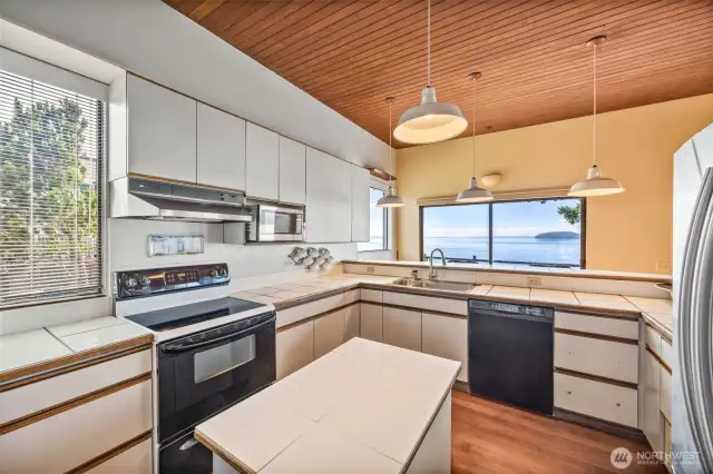 The kitchen offers generous counter space, a handy mini island with additional storage, and an abundance of cabinetry—all while enjoying beautiful water views right from the sink and prep areas.