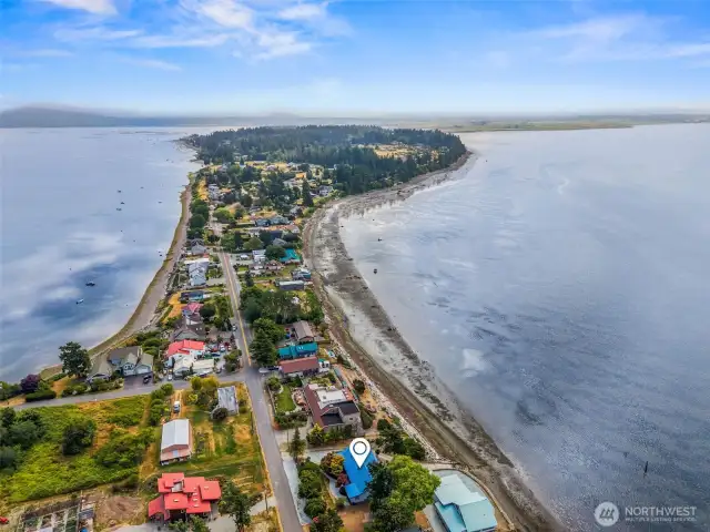 Aerial view looking east over the narrowest point of Samish Island, showcasing the property's unique setting between shoreline and tidelands with expansive views across Padilla Bay to the right and Samish Bay to the left.