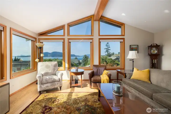 Spacious living room with walls of windows showcasing the stunning water and island views. Vaulted ceilings for an aerie feel. On a clear night you can even see up to Canada!